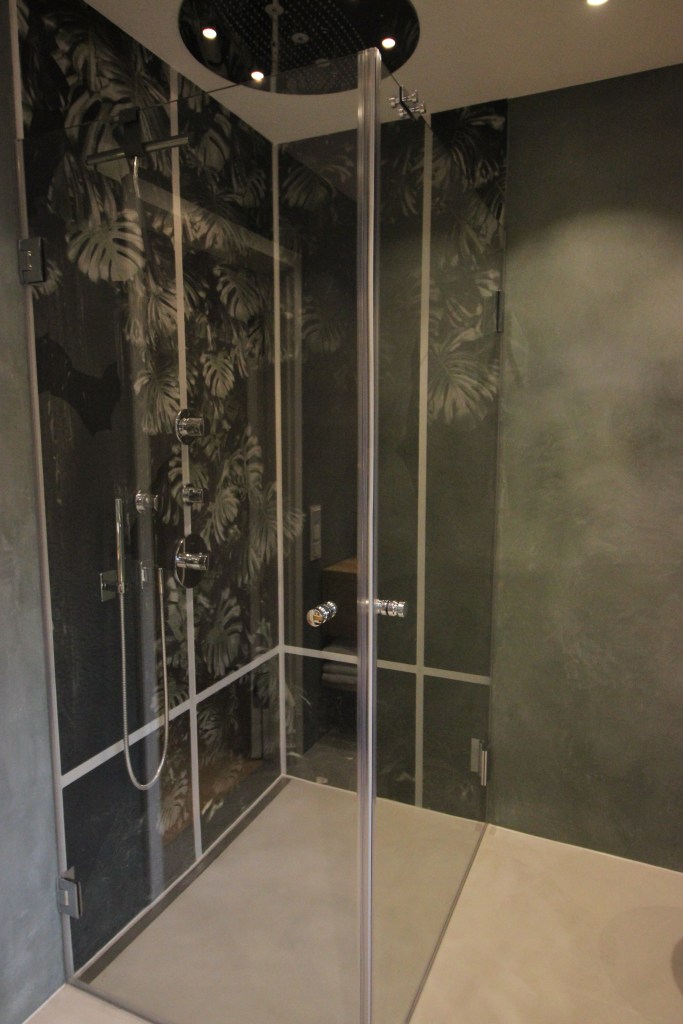 Moderne Dusche mit Glaswänden und Blattmuster, elegante Armaturen und Regenbrause.